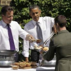 Cameron y Obama sirven una hamburguesa a un soldado durante una barbacoa.
