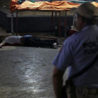 Un policía frente a un hombre asesinado en Acapulco.