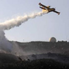 Un avión cisterna descarga agua sobre un incendio.