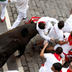 Un toro de la ganadería extremeña de Jandilla coge a un mozo en el tramo de la Plaza Consistorial de Pamplona durante el séptimo encierro de San Fermín 2018