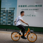 Un joven pasa en bicicleta ante un anuncio de un complejo de apartamentos en Pekín. MARK R. CRISTINO