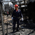 Un bombero inspecciona una de las viviendas quemadas por las llamas en la ciudad de Mati, próxima a Atenas.