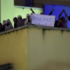 Algunos de los amotinados muestran un cartel que pide 'Libertad', en la azotea del CIE de Aluche.