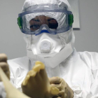 Una auxiliar se coloca el traje de protección contra el ébola