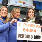 La lotera Ana María González (derecha) sujeta el cartel de premio con sus hijas y la agraciada Beatriz Pérez, a su lado.