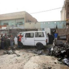 Varios iraquíes observan los restos del ataque con un coche bomba.