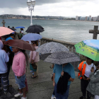 Turistas con paraguas ayer en Gijón. PACO PAREDES