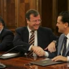 Antonio Silván estrecha la mano de Mario Amilivia, tras la firma, en presencia de Eduardo Fernández