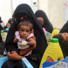 Mujeres yemenís sostienen a sus hijos mientras esperan el reparto de comida en la ciudad de Al Hudayda, en la costa oeste del país.