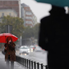 Dos transeúntes caminan entre la lluvia por las calles del centro de Madrid. MARISCAL