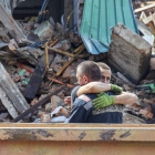 Dos bomberos se abrazan tras recoger los restos de civiles tras un bombardeo.  SERGEY KOZLOV