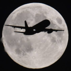 Un avión se acerca al aeropuerto de Heathrow (Londres) con la luna llena al fondo.