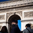 Un turista se protege frente al Arco del Triunfo de París.
