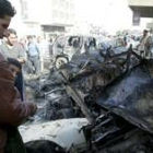 Un iraquí inspecciona los restos de un coche bomba en la plaza de Al-Tahrir del centro de Bagdad