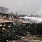 Junto a un montón de cadáveres calcinados, coches destruidos, y bomberos y curiosos en el lugar