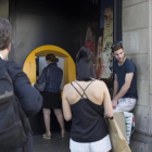 Varias personas esperan para operar en un cajero de una oficina de CaixaBank en la plaza de Catalunya.