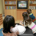 Tres niños ven la televisión en un centro de acogida.