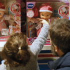 Una niña mira una muñeca en un escaparate.