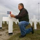 Un hombre coloca una bandera cubana en la cruz de su padre