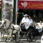 Turistas pasan en un coche de caballos por delante de la sede central de Cajasur.