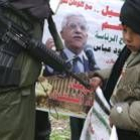 Un niño palestino delante de un cartel de Abú Mazen en Hebrón