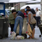 Un grupo de personas cogen comida caducada de containers, en Barcelona.