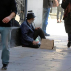 Un indigente pide ayuda a los traseúntes en una calle de Barcelona, ayer.