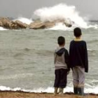 Dos niños observan las fuertes olas que el temporal levantó en L'Escala en Gerona