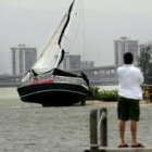 Un hombre observa un bote encallado en Key Biscayne, Miami