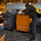 Un joven busca comida en un contenedor de basura orgánica, en Barcelona.