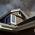 Una columna de humo emerge tras una casa en San Marcos, condado de San Diego (California).