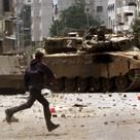 Un joven palestino lanza piedras contra tanques del Ejército israelí, ayer, en Gaza