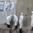 Grafiteros limpian las pintadas para saldar la multa que les ha puesto el Ayuntamiento.