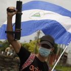 Un joven manifestante alza su arma artesanal y la bandera nacional de Nicaragua contra el régimen de Ortega.