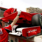 Una grúa retira el monoplaza de Alonso despues de que sufriera un golpe en el chasis.