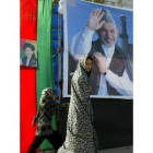 Niñas pasan por delante del cartel electoral de Karzai.
