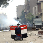 Un manifestante muestra una bandera egipcia a la policía, detrás de la barricada.