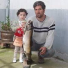 Manuel González muestra la trucha pescada acompañado de su sobrina Andrea