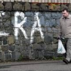 Un hombre camina ante un grafitti del IRA en el oeste de Belfast