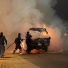 Dos bomberos tratan de apagar un coche incendiado durante los disturbios protagonizados por aficionados al fútbol en El Cairo el pasado 8 de febrero.