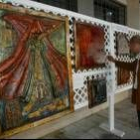 Uno de los pintores muestra sus obras, apoyadas frente a la fachada del I.E.S. Gil y Carrasco
