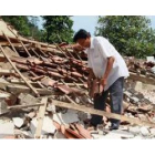 Dos hombres intentan rescatar algunas de sus pertenencias sepultadas bajo los escombros de su casa.