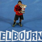 Nadal celebra en el centro de la pista y con el trofeo de campeón, su primer título en Australia