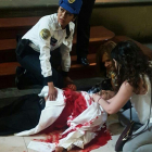 Dos mujeres y una oficial de la policía de Ciudad de México, intentan ayudar al sacerdote apuñalado