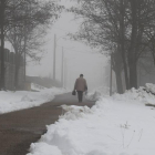 Un hombre camina por una carretera nevada en León.