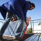 Un hombre instala placas fotovoltaicas en la cubierta de un edificio.