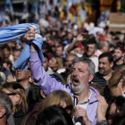 Un hombre empuña la bandera argentina entre la multitud que ha tomado las calles de Buenos Aires para protestar por la situación económica del país.