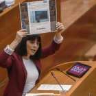 Sandra Miguez muestra, en el pleno de las Corts, un tuit del grupo popular en el que se hace eco del titular de una entrevista a un profesor, criticado por la diputada de Podemos durante su intervención.
