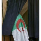 Un argelino deposita su voto atabiado con la bandera del país
