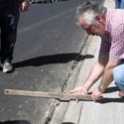 Un vecino muestra cómo el asfalto está por encima de la acera